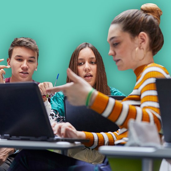 Three people in a classroom setting with laptops, one pointing at a screen.